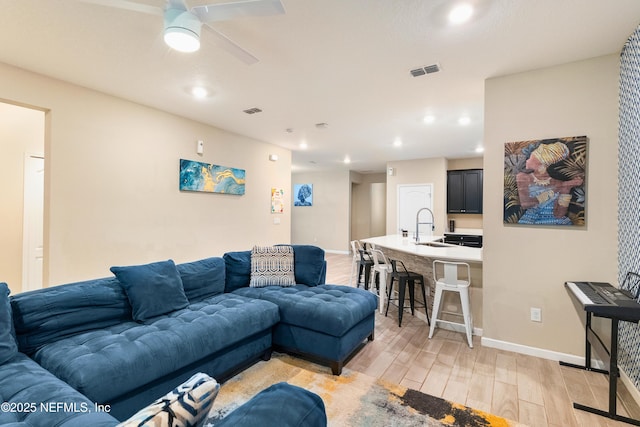 living room with sink, ceiling fan, and light hardwood / wood-style flooring