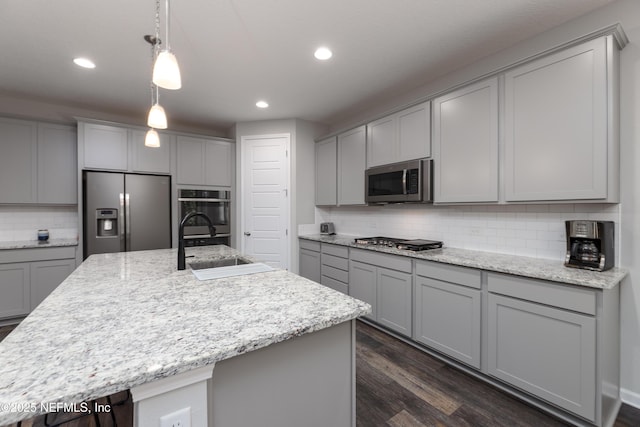 kitchen featuring a kitchen island with sink, sink, and appliances with stainless steel finishes