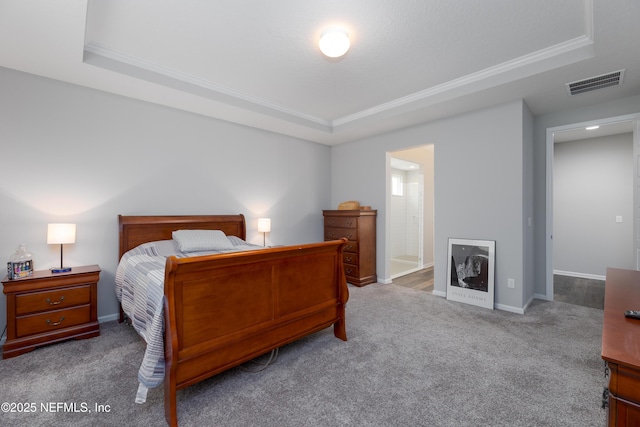 carpeted bedroom with ensuite bathroom and a raised ceiling