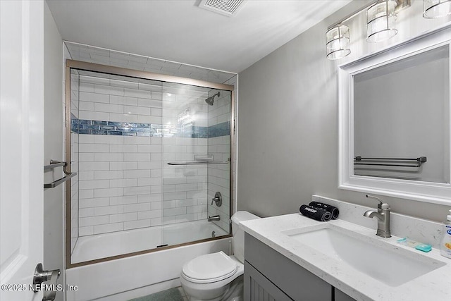 full bathroom featuring vanity, combined bath / shower with glass door, and toilet