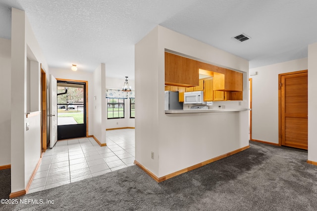 kitchen with light carpet, a notable chandelier, stainless steel refrigerator, and kitchen peninsula