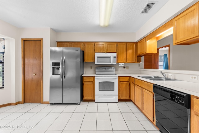 kitchen featuring sink, a textured ceiling, light tile patterned floors, plenty of natural light, and white appliances