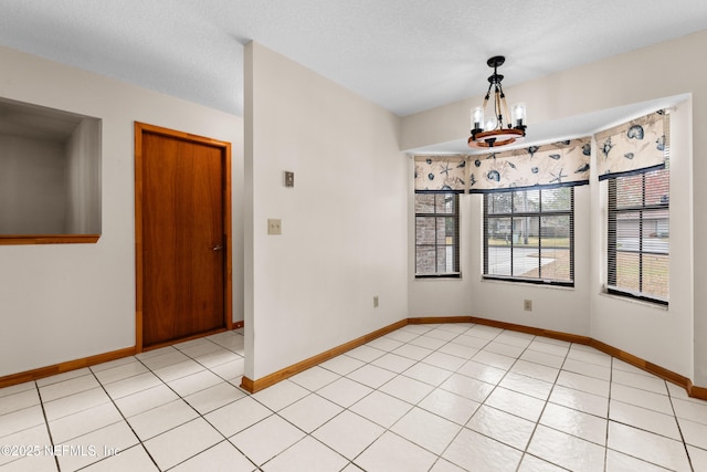 tiled empty room featuring an inviting chandelier and a textured ceiling