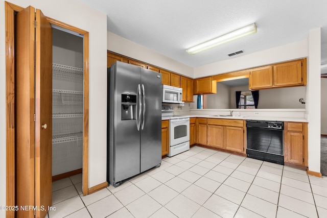 kitchen with white appliances, sink, a textured ceiling, and light tile patterned floors