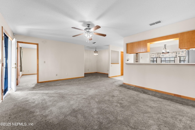 unfurnished living room featuring ceiling fan with notable chandelier, light carpet, and a textured ceiling