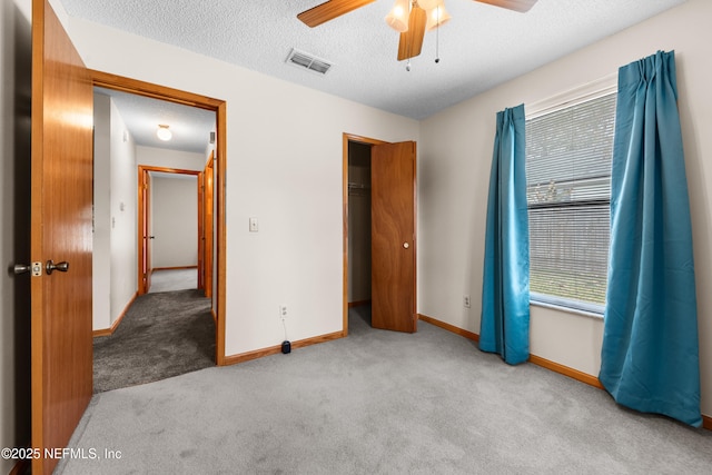 unfurnished bedroom featuring light carpet, ceiling fan, a closet, and a textured ceiling