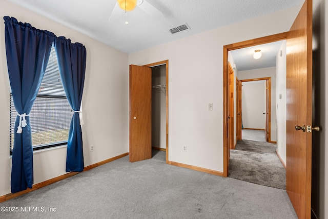 unfurnished bedroom featuring ceiling fan, light carpet, a textured ceiling, and a closet