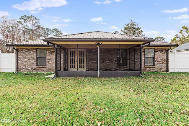 back of property with a lawn, a sunroom, and ceiling fan