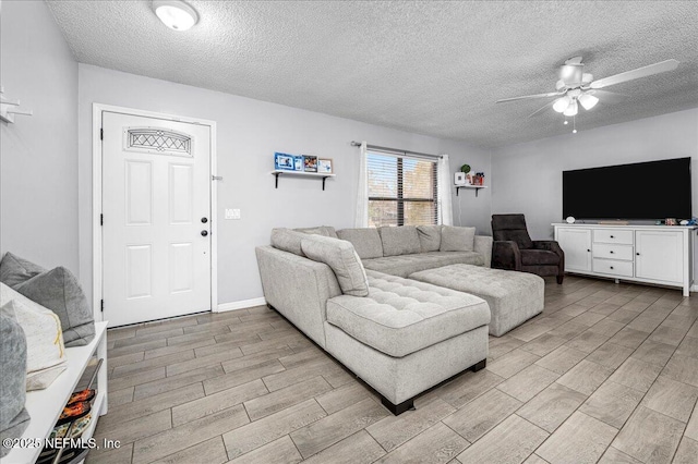 living room with ceiling fan and a textured ceiling