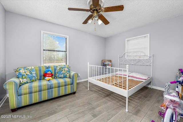 bedroom with ceiling fan, wood-type flooring, and a textured ceiling