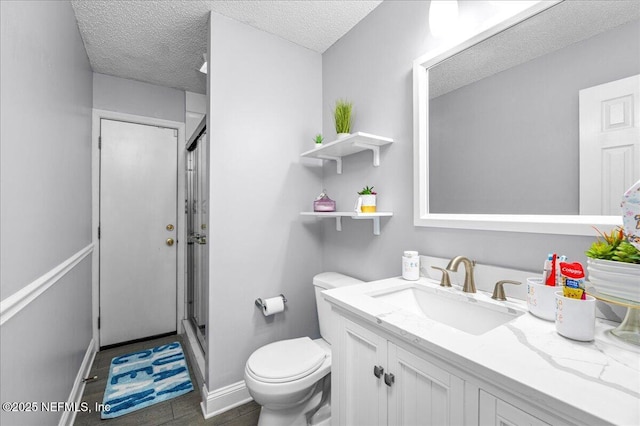 bathroom featuring vanity, toilet, an enclosed shower, and a textured ceiling