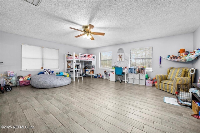 game room featuring ceiling fan, light hardwood / wood-style flooring, and a textured ceiling