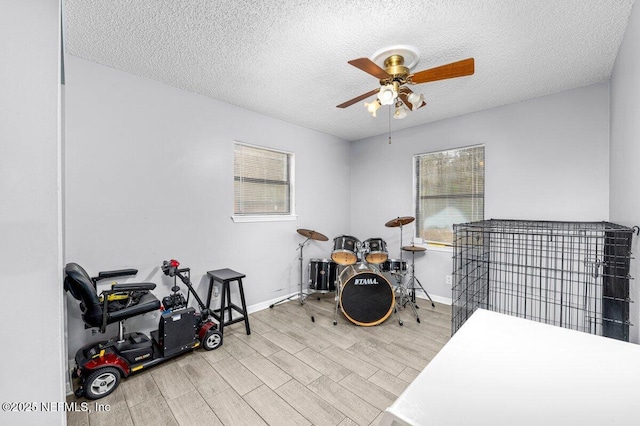 misc room featuring ceiling fan, a textured ceiling, and light hardwood / wood-style flooring