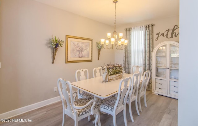 dining room featuring baseboards, a notable chandelier, and light wood finished floors