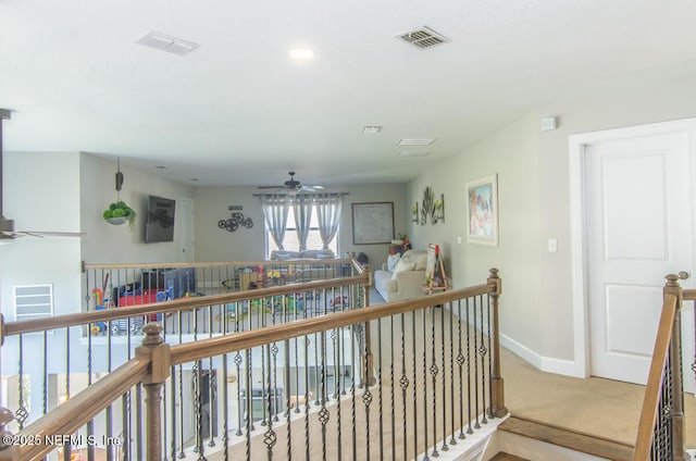 corridor with baseboards, visible vents, and an upstairs landing