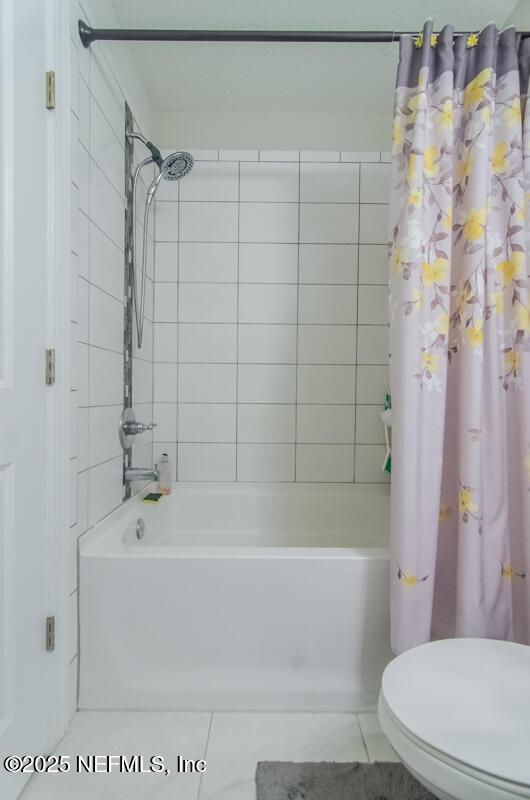 bathroom with tile patterned flooring, shower / bath combo with shower curtain, and toilet