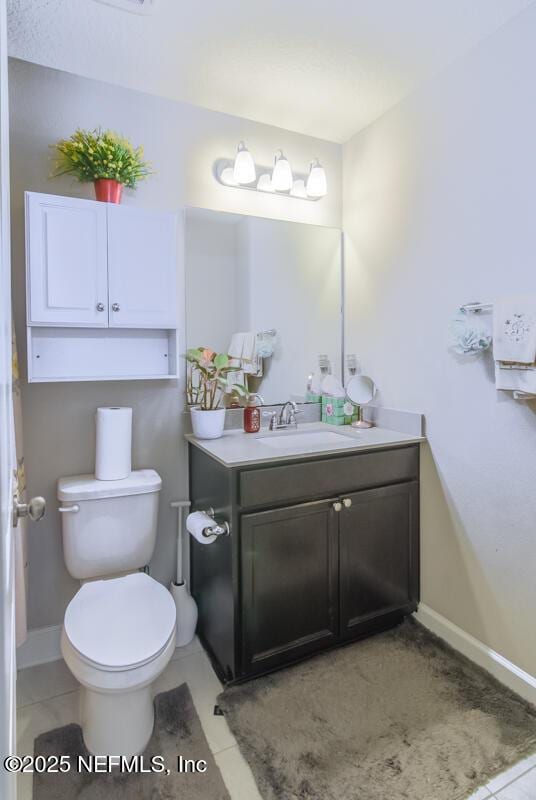 bathroom featuring baseboards, toilet, vanity, and tile patterned floors