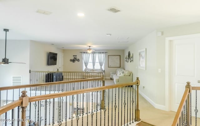 hallway with visible vents, carpet flooring, baseboards, and an upstairs landing