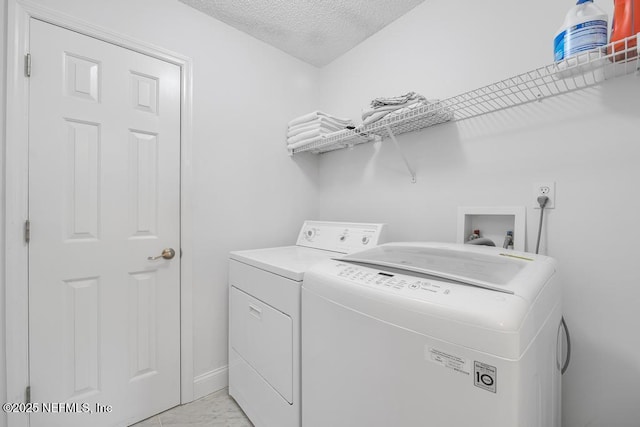 laundry room with a textured ceiling and washer and clothes dryer