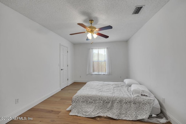 bedroom with wood-type flooring, ceiling fan, and a textured ceiling