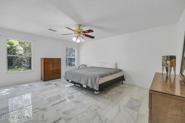 bedroom with ceiling fan and a textured ceiling