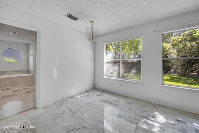 spare room featuring an inviting chandelier and a textured ceiling