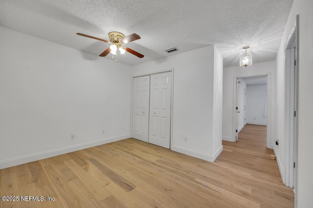 unfurnished bedroom with ceiling fan, a closet, a textured ceiling, and light wood-type flooring