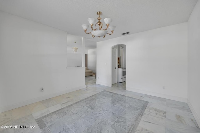 spare room with a notable chandelier and a textured ceiling