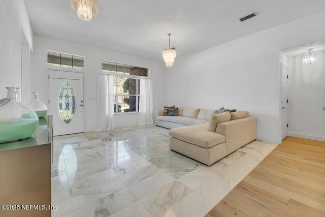 living room featuring a notable chandelier, hardwood / wood-style flooring, and a textured ceiling