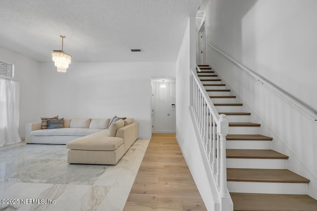 living room with light hardwood / wood-style flooring, a chandelier, and a textured ceiling