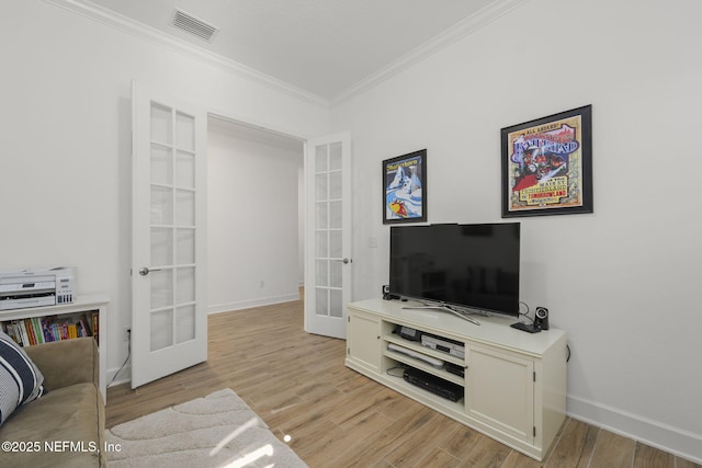 living room with ornamental molding, light wood-type flooring, and french doors