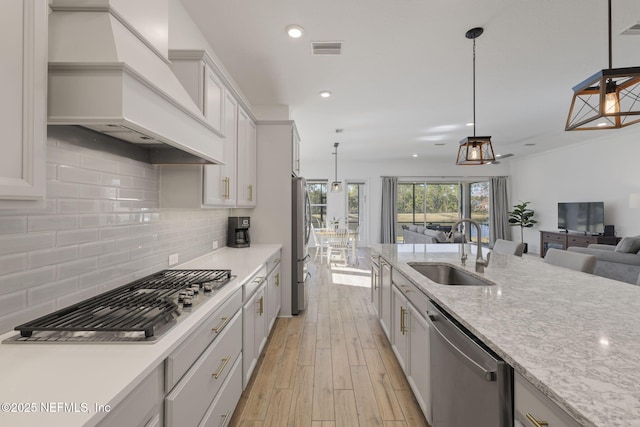 kitchen featuring pendant lighting, sink, appliances with stainless steel finishes, tasteful backsplash, and custom exhaust hood