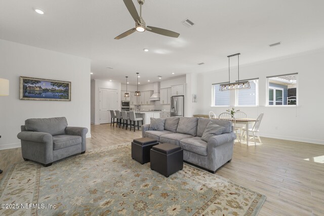 living room with light hardwood / wood-style flooring and ceiling fan