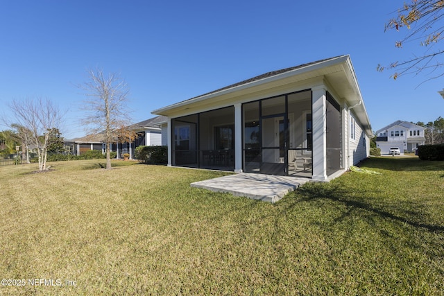 rear view of house with a sunroom, a patio area, and a lawn