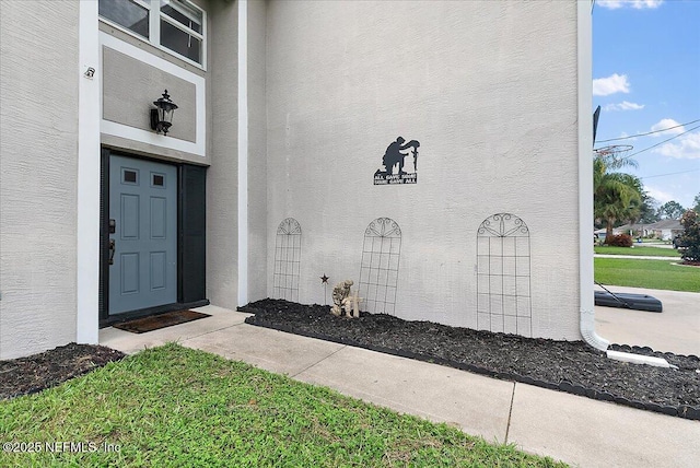 view of exterior entry with a yard