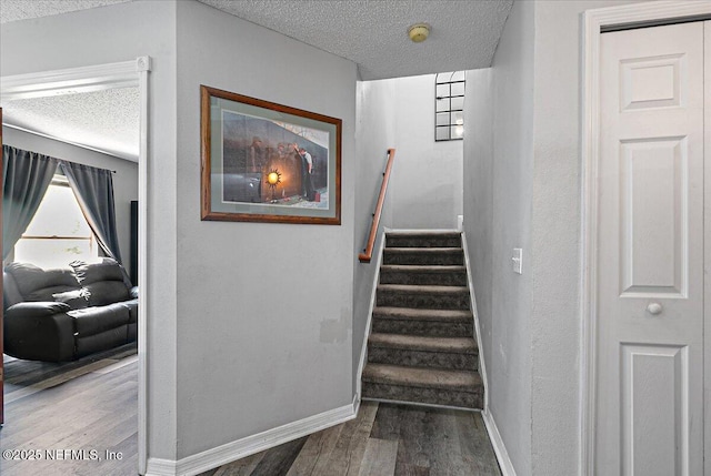 stairway with hardwood / wood-style floors and a textured ceiling