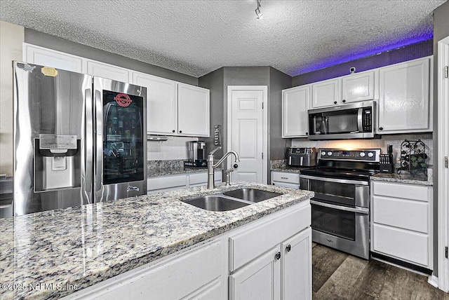 kitchen with dark wood-type flooring, sink, stainless steel appliances, light stone countertops, and white cabinets