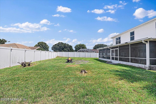 view of yard featuring a sunroom and an outdoor fire pit