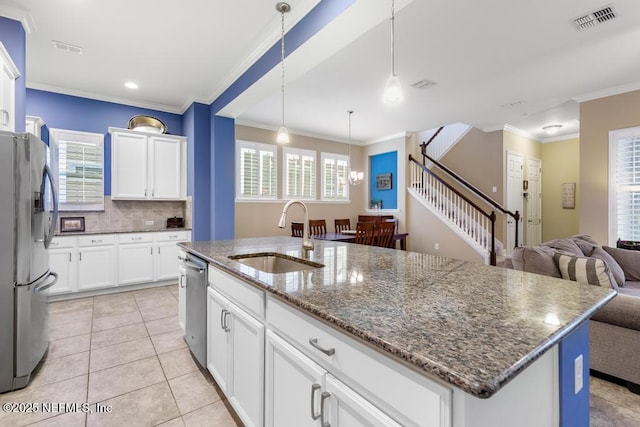 kitchen with appliances with stainless steel finishes, decorative light fixtures, white cabinetry, sink, and a center island with sink