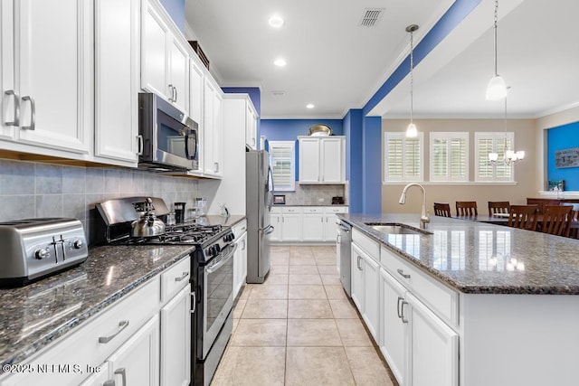 kitchen featuring pendant lighting, an island with sink, sink, white cabinets, and stainless steel appliances