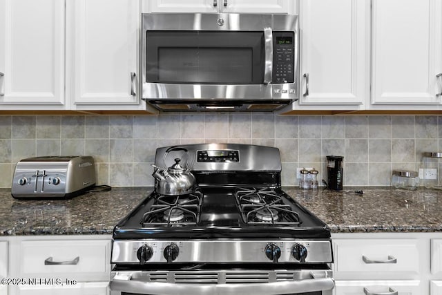 kitchen with stainless steel appliances, white cabinetry, tasteful backsplash, and dark stone counters