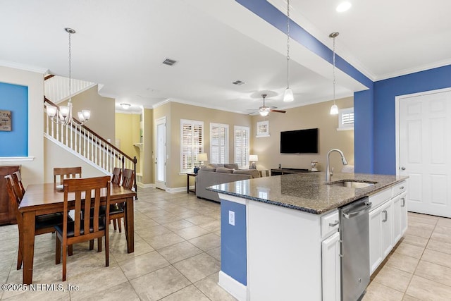 kitchen featuring sink, a kitchen island with sink, white cabinetry, hanging light fixtures, and dark stone countertops