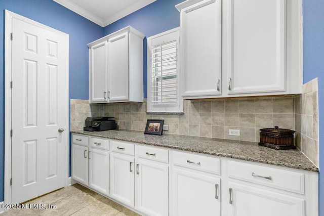 kitchen featuring tasteful backsplash, white cabinetry, dark stone counters, light tile patterned floors, and crown molding