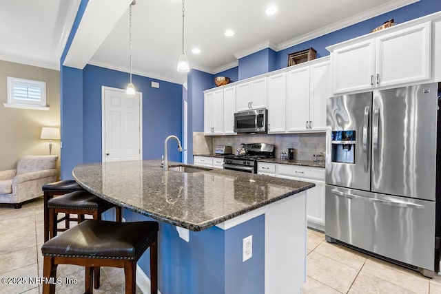 kitchen featuring an island with sink, appliances with stainless steel finishes, a breakfast bar, and white cabinets