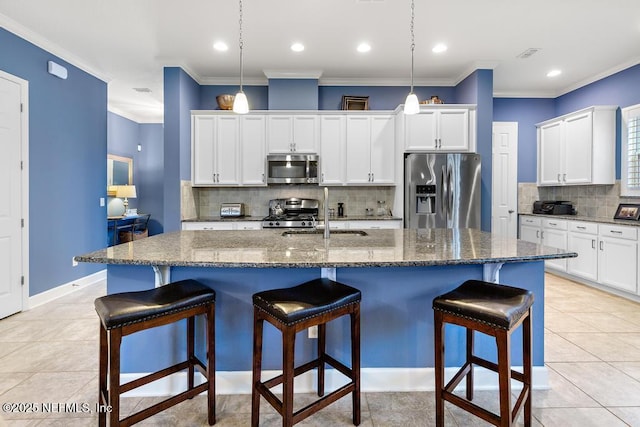 kitchen with pendant lighting, stainless steel appliances, and an island with sink