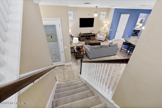 staircase featuring ceiling fan, ornamental molding, and tile patterned flooring