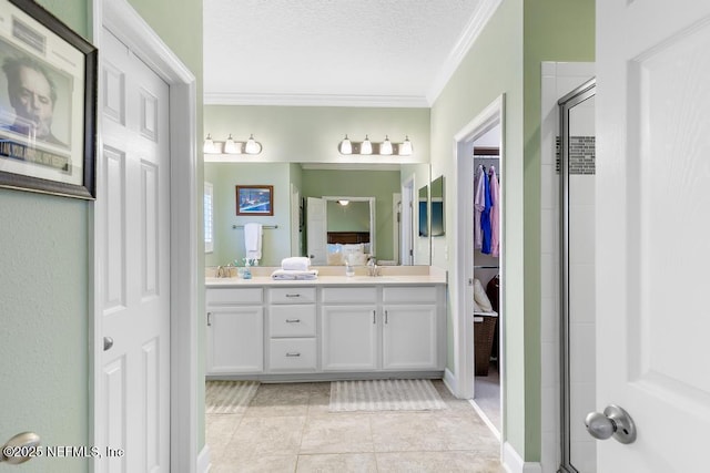 bathroom with tile patterned floors, a shower with shower door, crown molding, a textured ceiling, and vanity