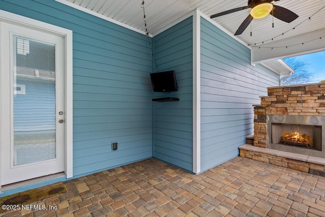 view of patio / terrace featuring ceiling fan and an outdoor stone fireplace