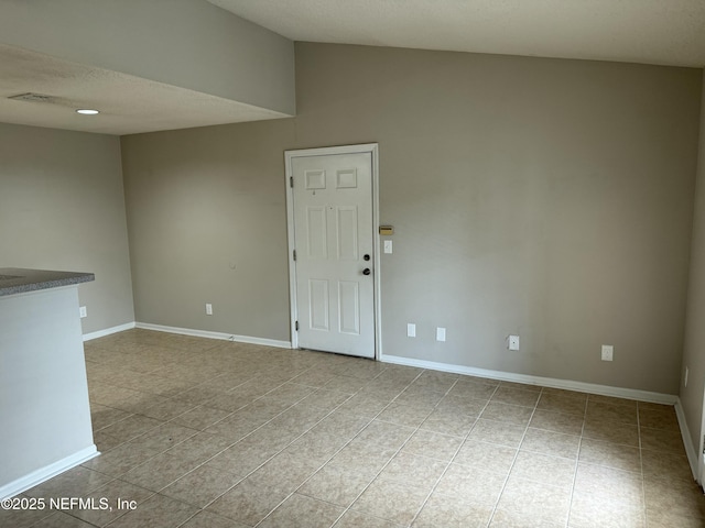 unfurnished room with vaulted ceiling and light tile patterned floors