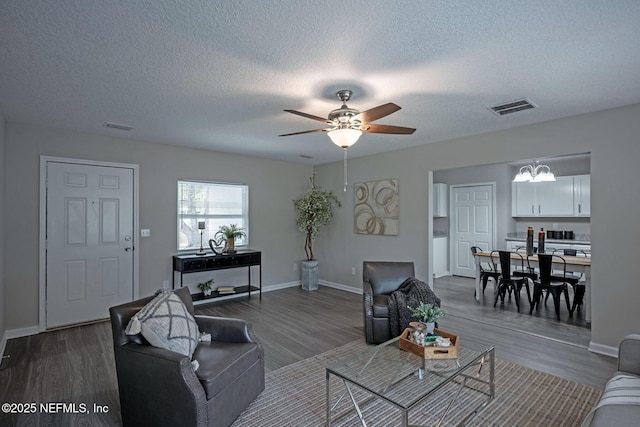 living room with hardwood / wood-style flooring, ceiling fan with notable chandelier, and a textured ceiling